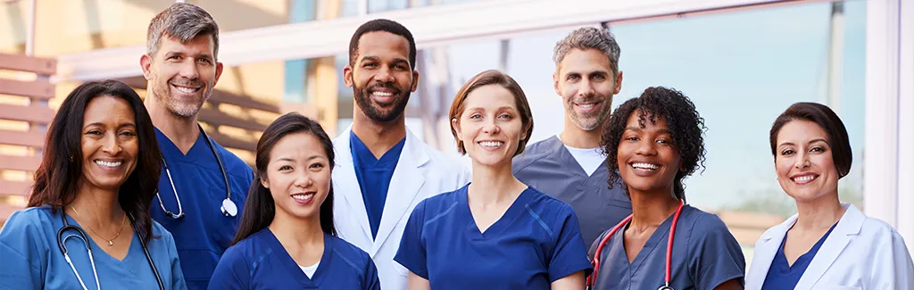 Nurse staffing workers smiling for a group photo outside a hospital.