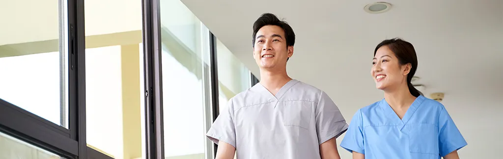 A couple of nurses walking at a hospital hallway.